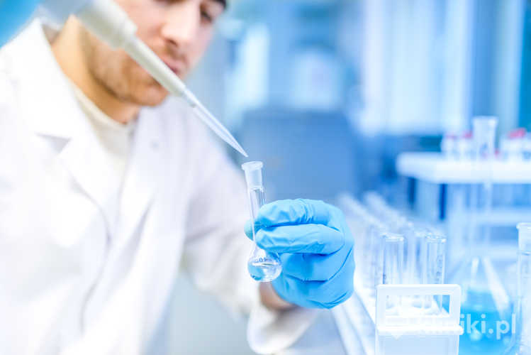 Naukowiec używa narzędzia medycznego do ekstrakcji cieczy z próbek w specjalnym laboratorium